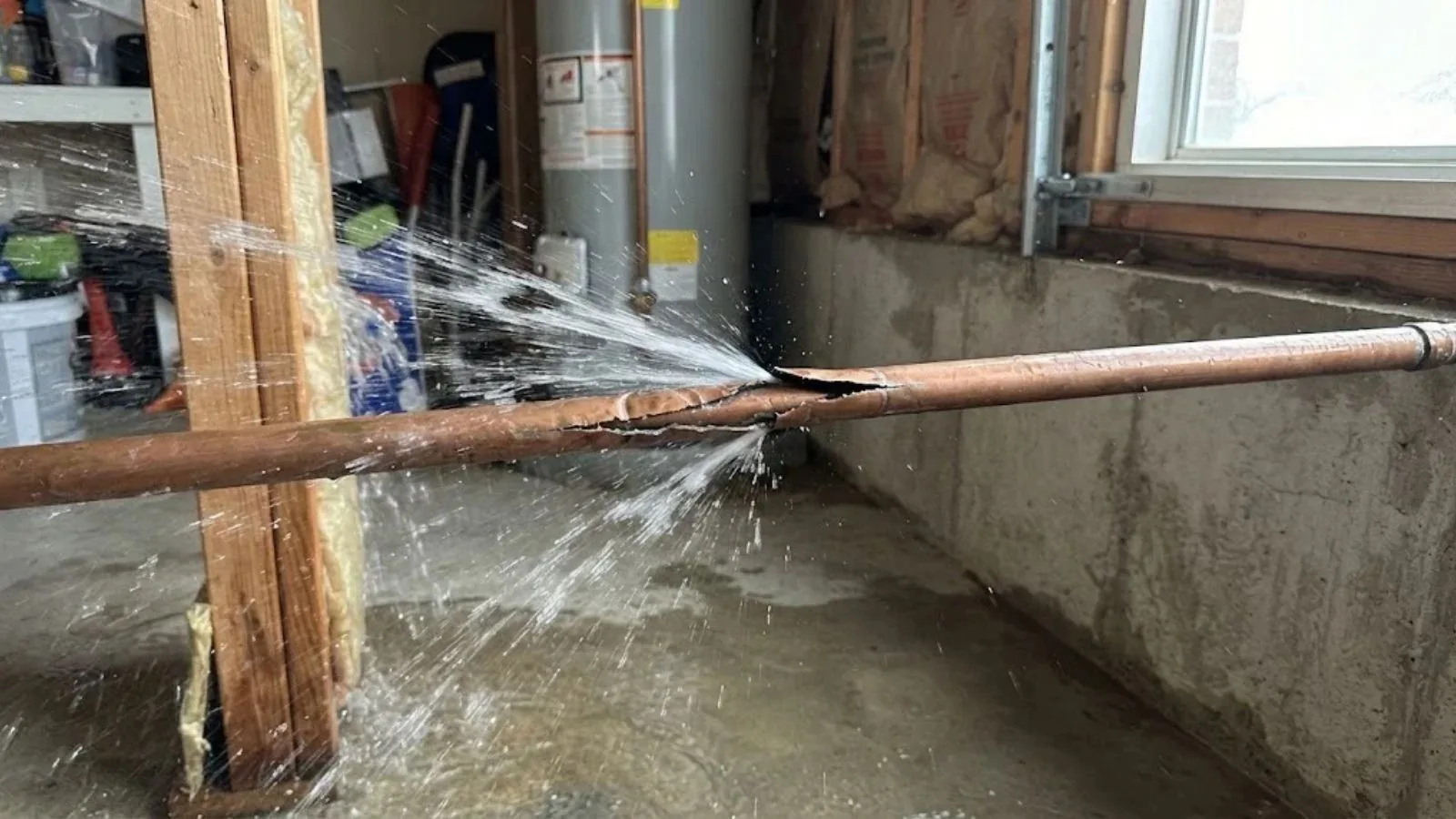 Burst copper pipe spraying water in a basement